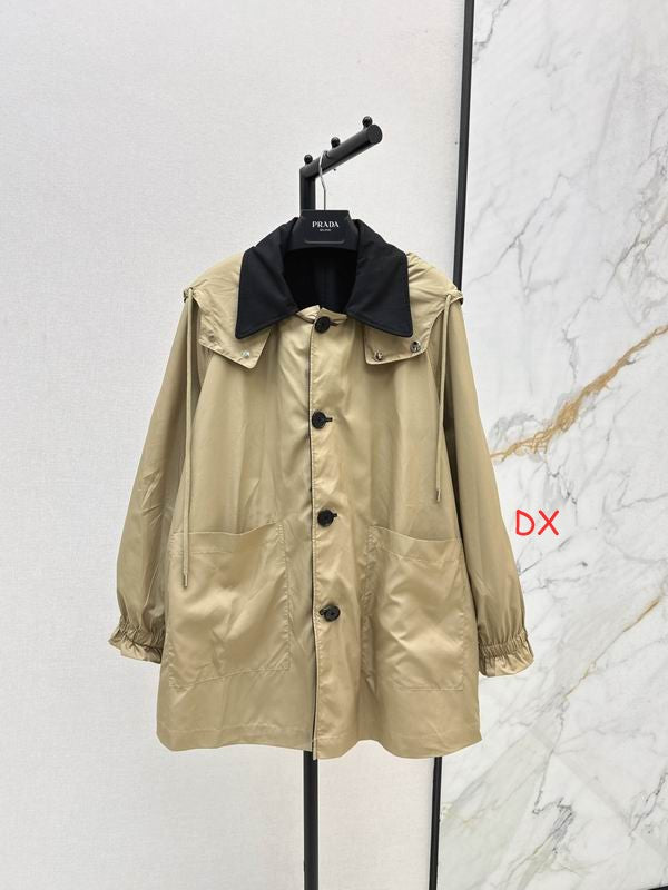 A beige Prada raincoat with a black collar, hanging on a black hanger against a split white and marble background.