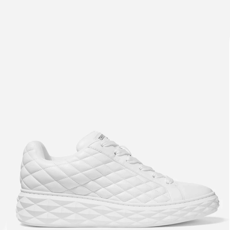 A white quilted leather sneaker with a chunky, geometrically patterned sole, shown from a side profile on a light gray background.