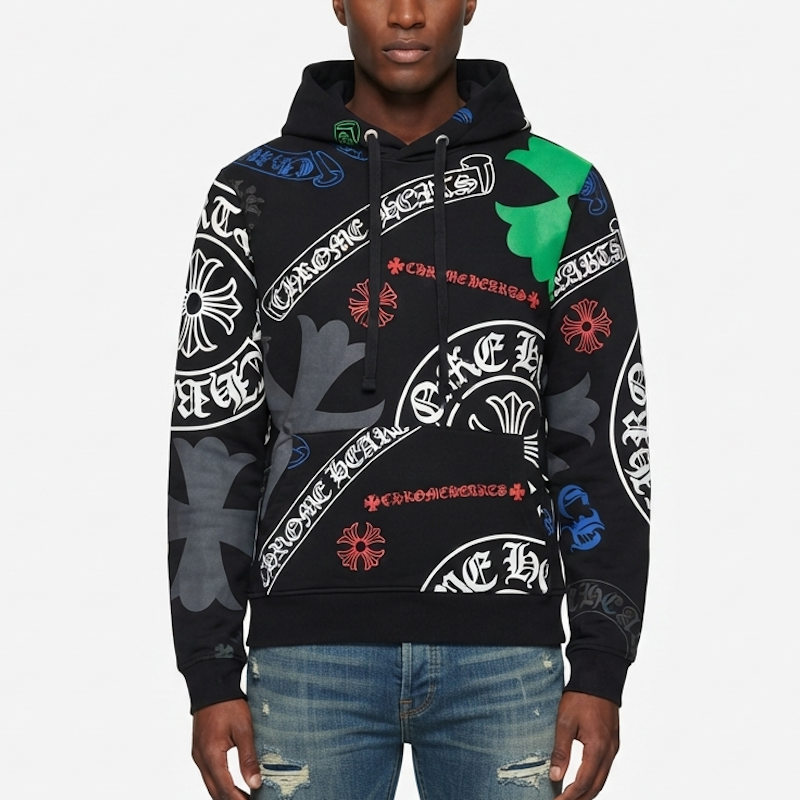 A man wearing a black hoodie with an all-over graphic print featuring white gothic-style lettering, red floral motifs, and green and gray camouflage elements, paired with blue jeans against a light gray background.