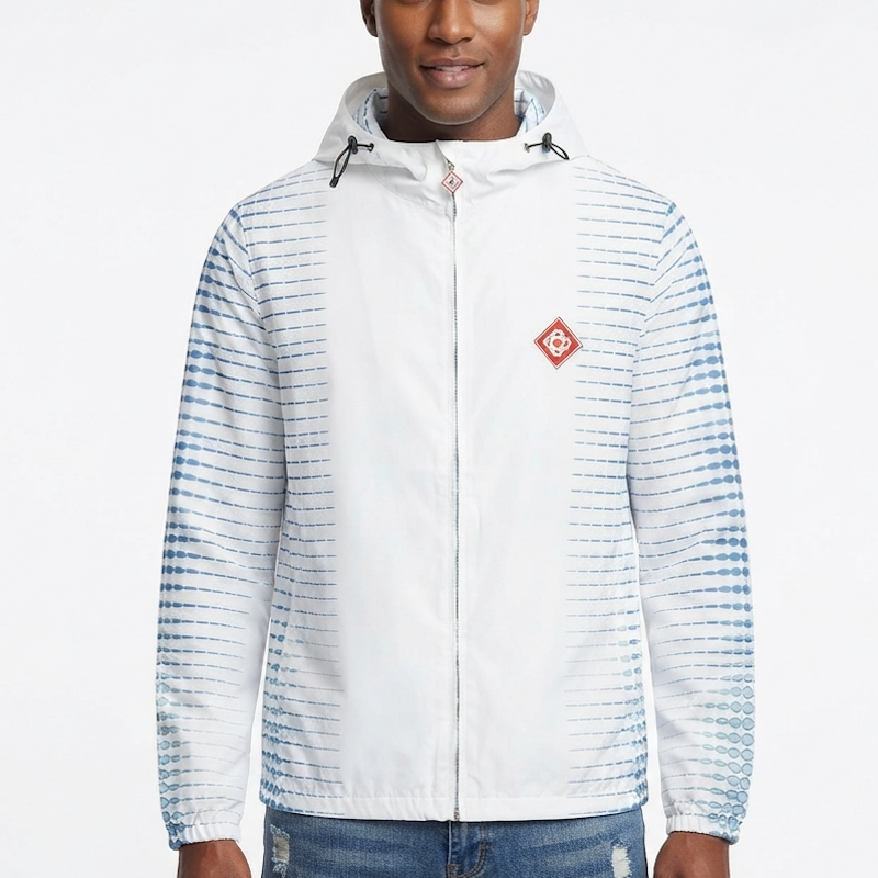 A man wearing a white hooded windbreaker jacket with blue tie-dye style horizontal stripes on the sleeves and sides, featuring a small red diamond-shaped logo patch on the left chest.