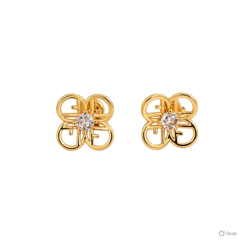 A pair of gold stud earrings featuring a stylized interlocking monogram design with a small clear gemstone at the center, shown on a plain white background.