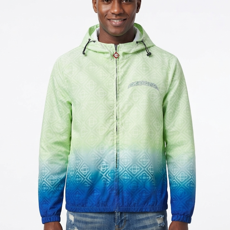 A man wearing a hooded zip-up jacket with a light green to blue gradient and a subtle geometric pattern, set against a plain white background.