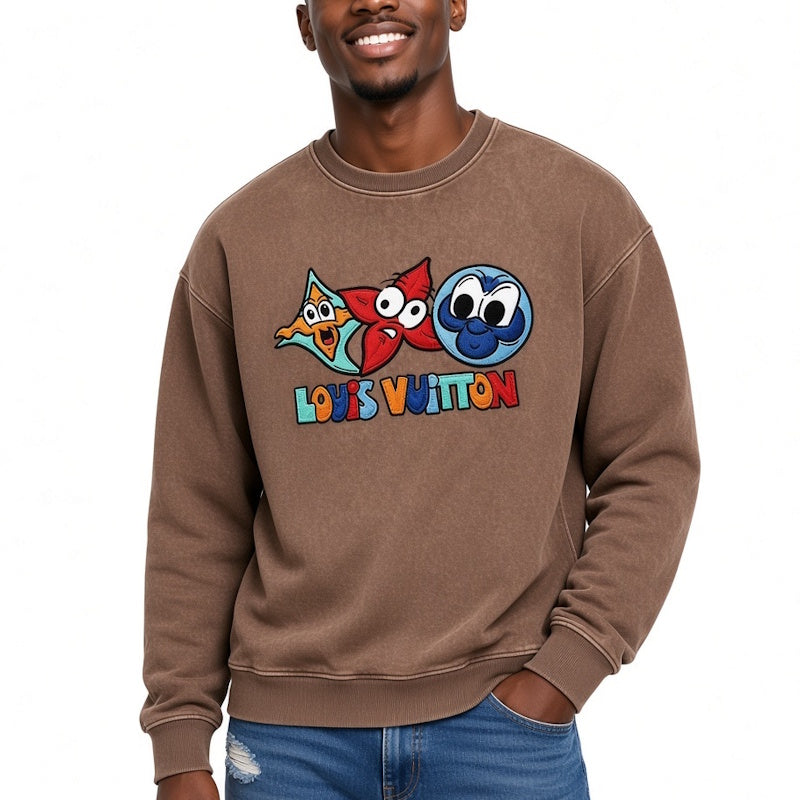 A man wearing a brown crewneck sweatshirt with a colorful graphic of cartoon characters and the text  across the chest, paired with blue jeans against a plain white background.