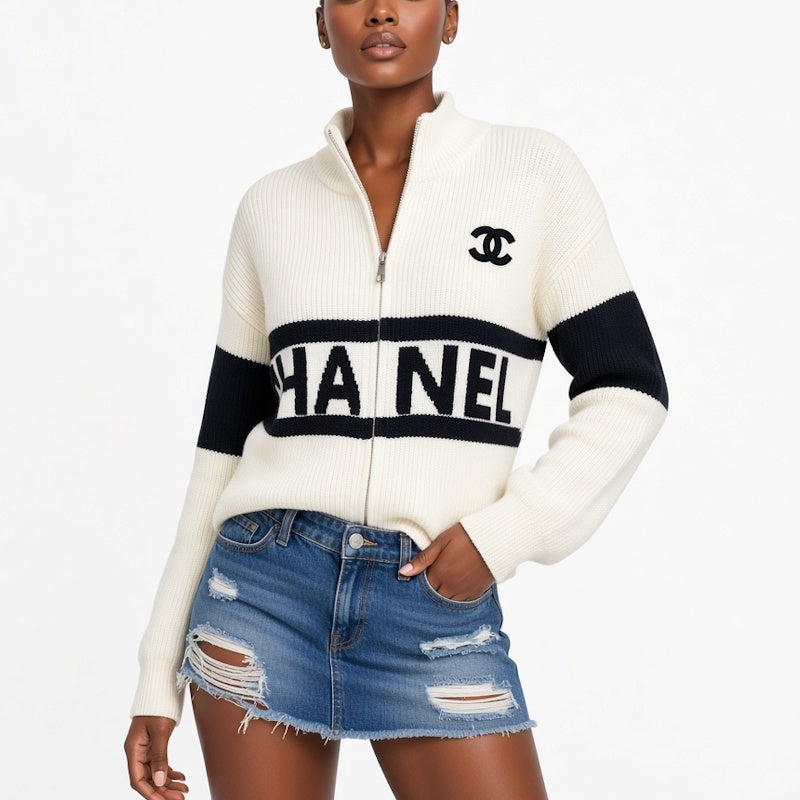 A model wears a zip-up knit sweater in off-white and black, featuring the brand's interlocking CC logo on the chest and 'CHANEL' text across the front. The model is also wearing a distressed denim mini skirt against a clean white background.
