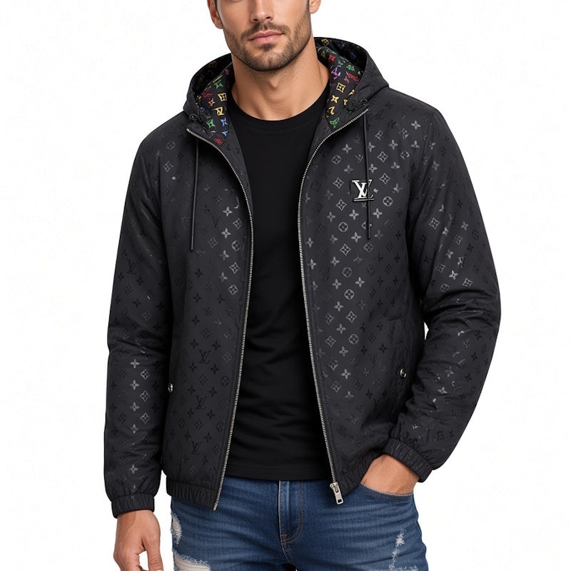 A man wearing a black Louis Vuitton hooded jacket with an all-over monogram pattern, a white LU logo on the chest, and a colorful patterned lining inside the hood, styled over a black t-shirt and blue jeans.