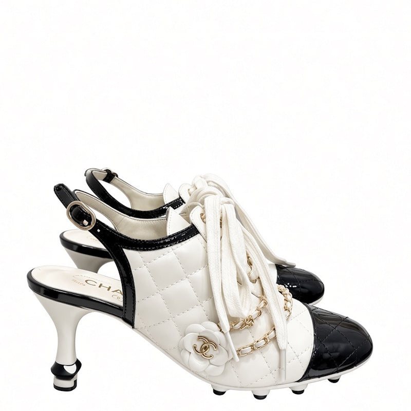 A pair of  high-heeled slingback shoes featuring a white quilted leather body, black patent leather toe caps and heel accents, white laces, and gold-tone chain and floral hardware.