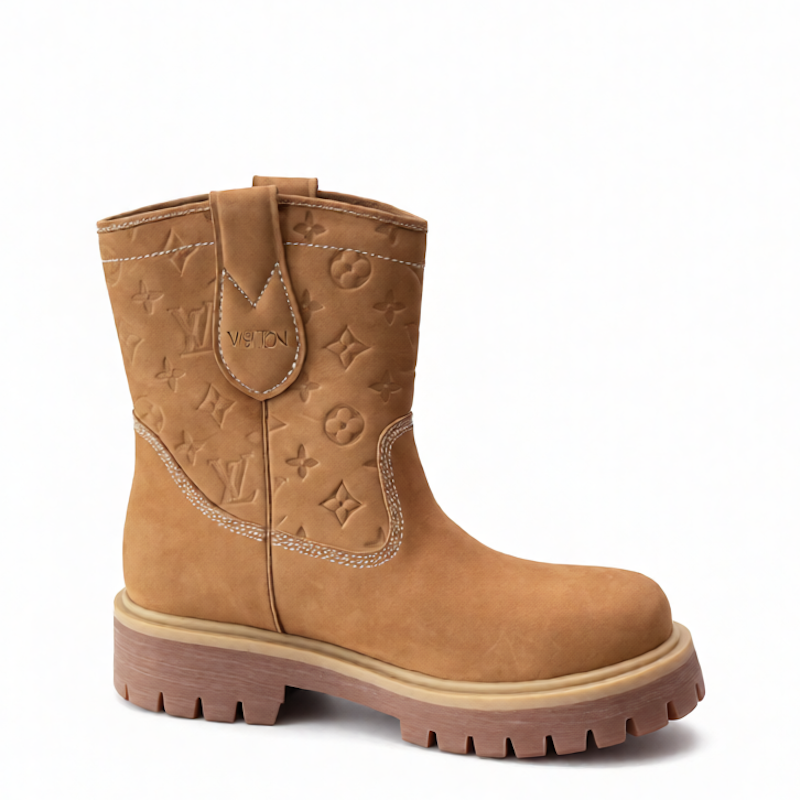 A tan suede western-style boot featuring an embossed Louis Vuitton monogram pattern on the shaft, a pull tab with 'LOUIS VUITTON' text, and a chunky brown lug sole, shown against a plain white background.