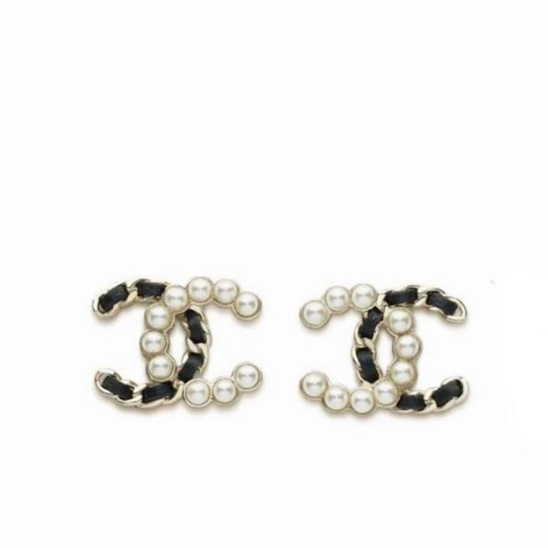 A pair of CC logo stud earrings featuring black and white leather trim, white faux pearls, and silver-tone metal settings, shown on a plain white background.